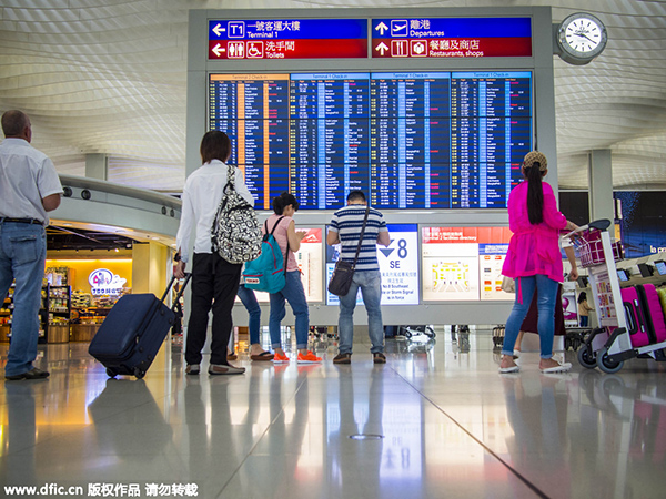 ہانگ کانگ کے بین الاقوامی ہوائی اڈے پر مسافر برقی بورڈ پر پروازوں کی آمد و رفت کے اوقات دیکھ رہے ہیں 