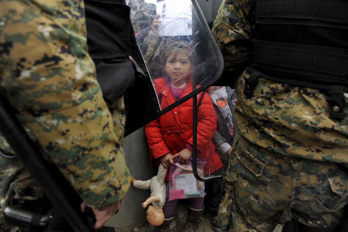 یورپ کے ممالک نے پہلے پہل تو شامی مہاجرین کو داخلے سے روکے رکھا۔ اس تصویر میں یونان اور مقدونیہ کی سرحد پر ایک ایک مہاجر بچی اپنے کھلونے کے ساتھ مقامی پولیس کے نرغے میں دکھائی دے رہی ہے